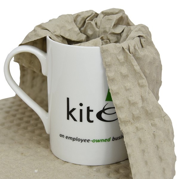 White mug with kite packaging logo, half wrapped in paper bubble wrap.
