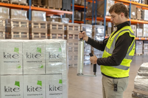 a man in hi vis hand wrapping a pallet in a warehouse