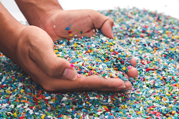 a pair of hands scooping coloured plastic pellets in their palm